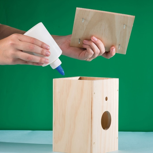 Stanley junior wooden DIY kit birdhouse being glued together by a person.
